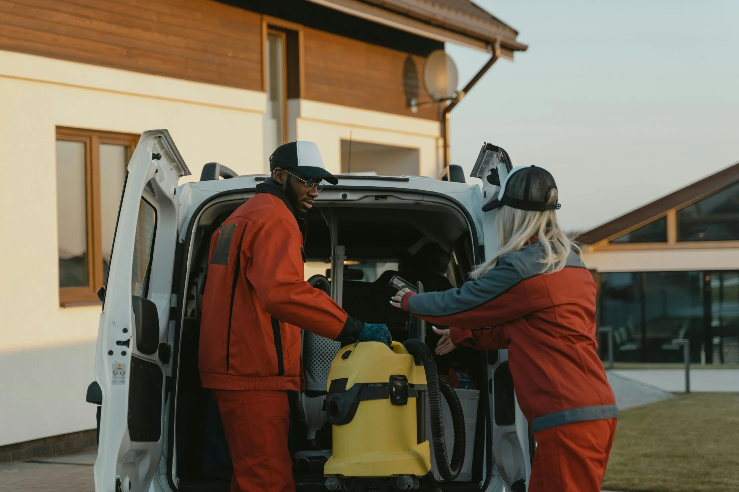 Service technicians loading equipment from a van at a residential property