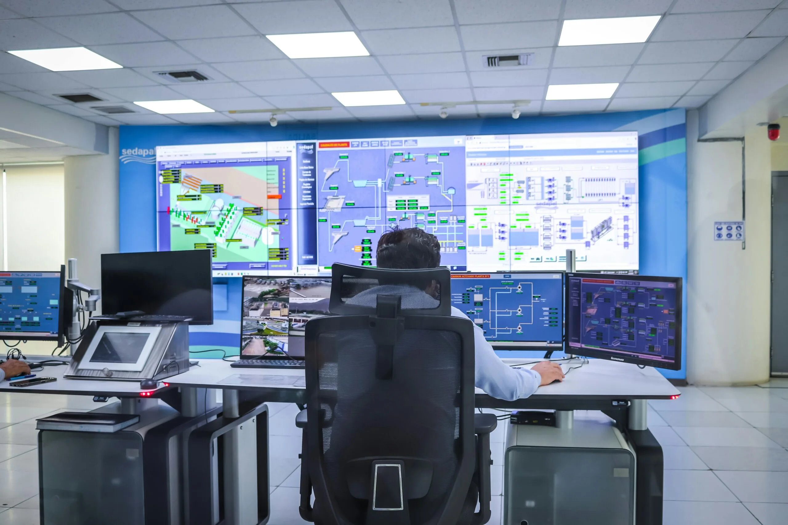 IT operations control room with multiple monitors showing system dashboards and network maps