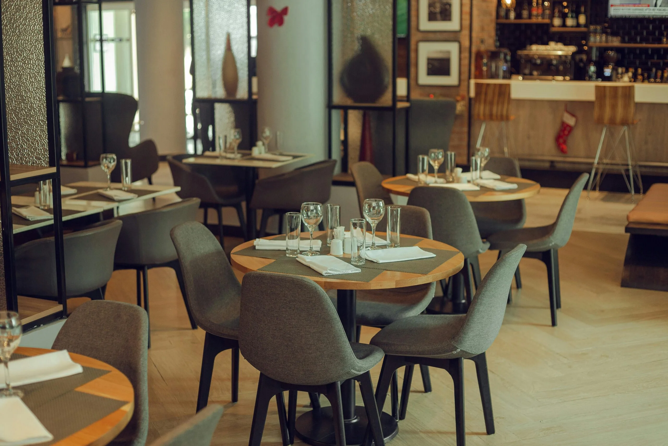 A well-lit restaurant dining room with neatly arranged tables and chairs ready for service